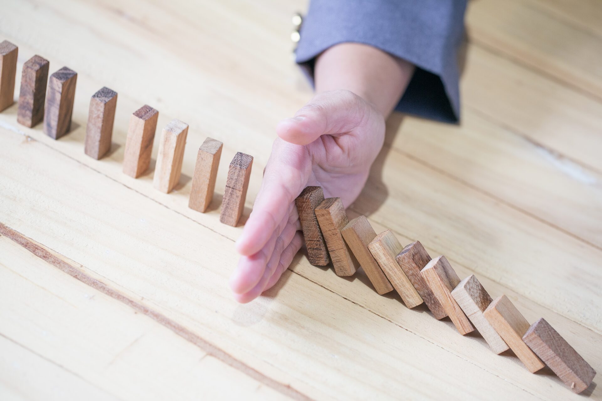 images of hand stopping domino effect with his finger. business crisis concept.